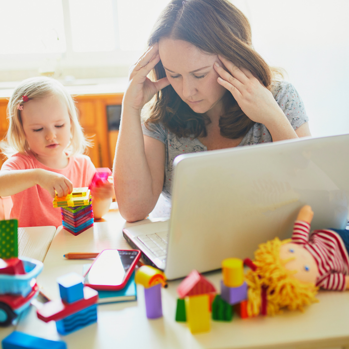 Stressed mum working while trying to entertain young child